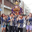 Men and women wearing happi coats and carrying a portable shrine at a Japanese festival